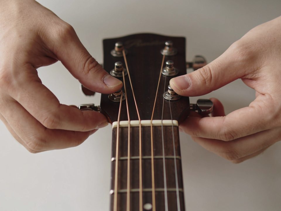 Gros plan mains accordant une guitare vue dessus
