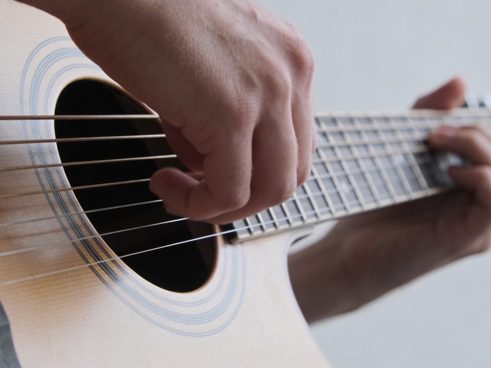 gros plan mains jouant arpèges sur guitare