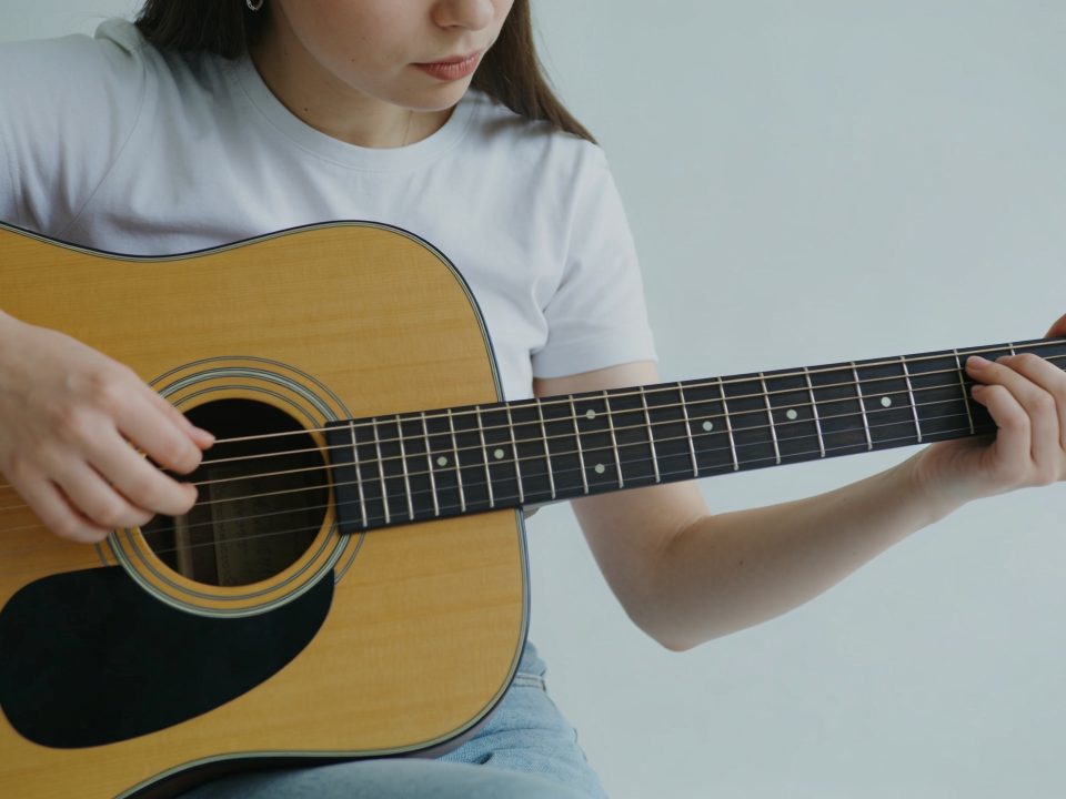 jeune femme assise gratte une guitare acoustique