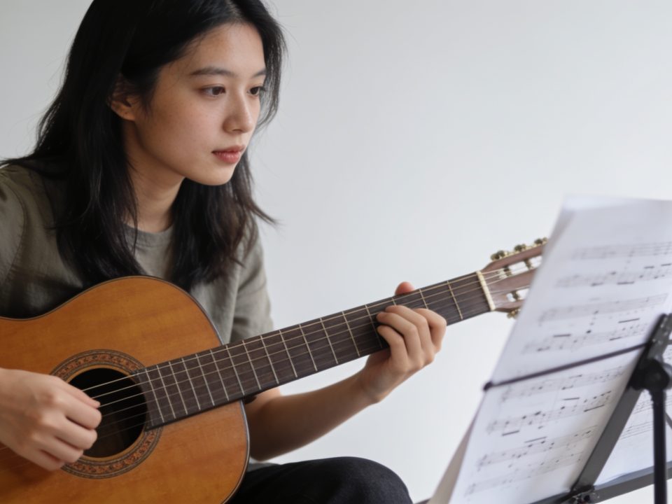 Jeune femme assise jouant guitare acoustique partitions