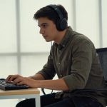 jeune producteur casque sur les oreilles devant ordinateur