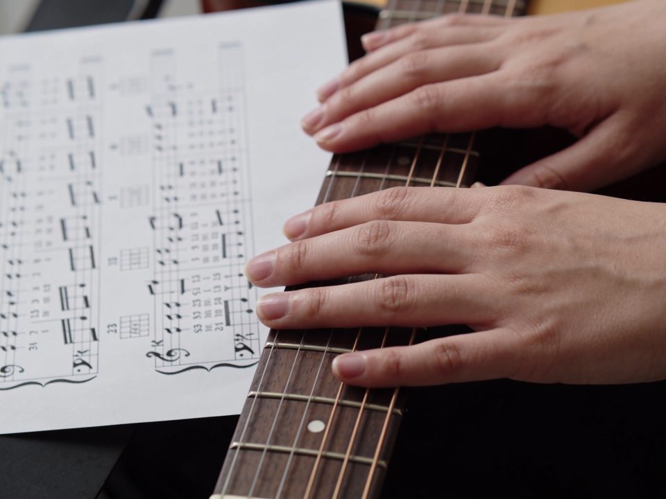 mains sur manche de guitare et tablature imprimee