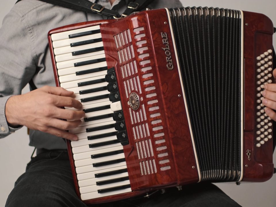 musicien assis jouant un accordéon diatonique rouge