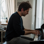 Homme assis au piano composant musique pour cinema francais