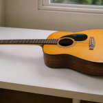 Guitare acoustique posee horizontalement sur table blanche