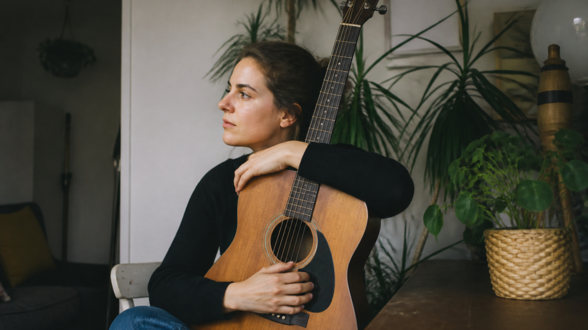 Personne assise tenant une guitare acoustique contre sa poitrine