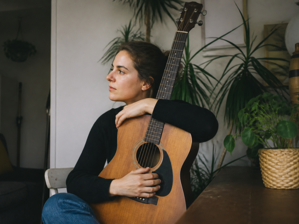 Personne assise tenant une guitare acoustique contre sa poitrine